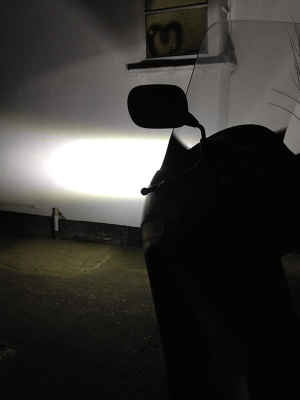In order to try and show the light cast onto a white surface, I've parked the bike diagonally across my driveway, pointing at the side of the house. You can see where the focus of the lights are now, and it's pretty high, even though the wall is very close to the front of the bike.