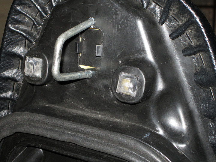 Two plastic bumpers stuck to the bottom of the seat covering the holes used by the rubber OEM version